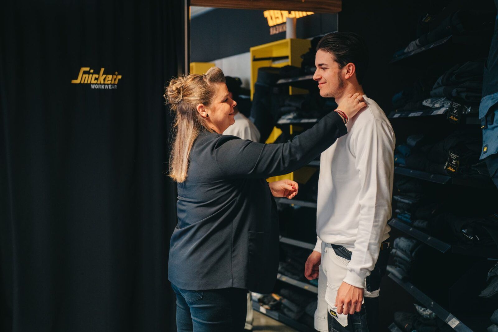 Medewerker van Beerendruk helpt klant met passen van kledij