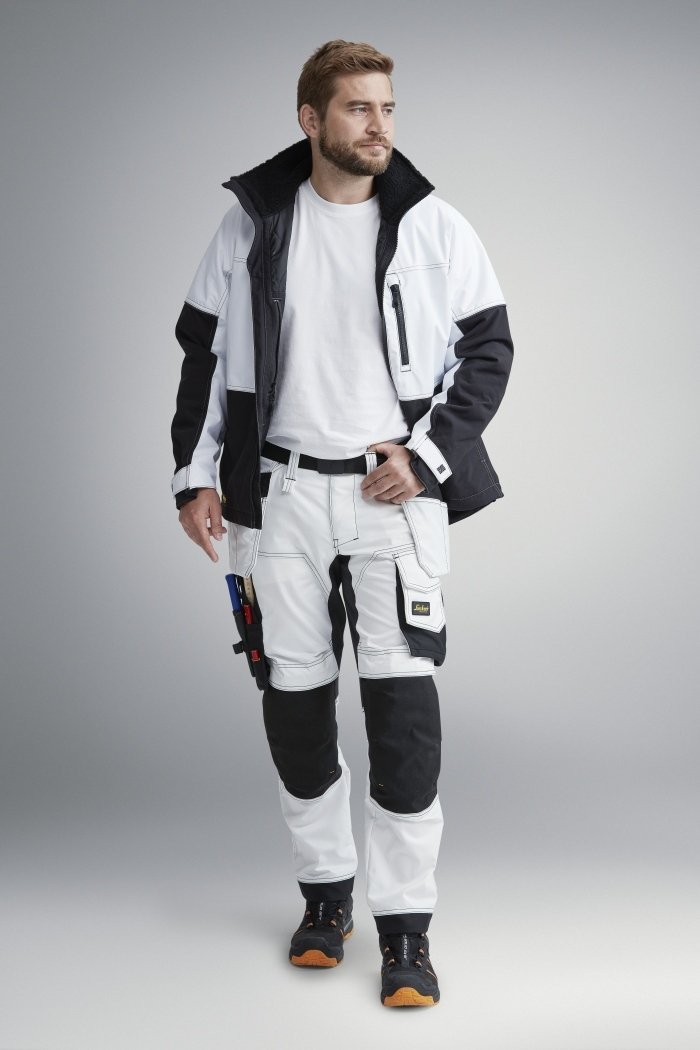 Man in witte en zwarte werkkleding met verschillende zakken, geschikt voor diverse klussen. Voor ieder wat wits! Comfortabel en functioneel ontwerp.